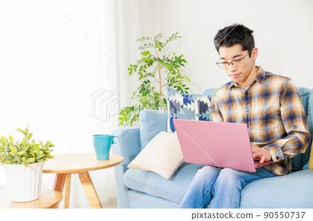 A man opening a laptop in the living room A man opening a laptop in the living room 90550737