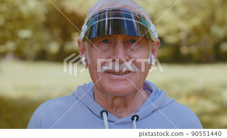 Portrait of athletic senior sport runner man wearing earphones listening music, smiling, cardio 90551440