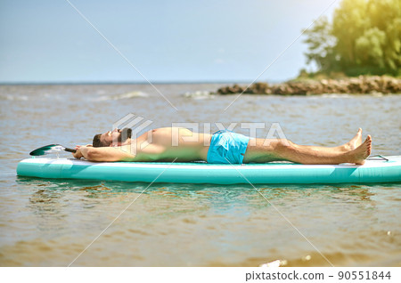 A man in blue swim wear lying on a kaya and sunbathing 90551844