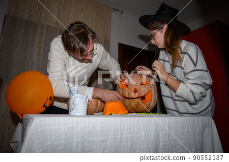 Father and daughter carving pumpkin, Jack o lanterns on Halloween party at the kitchen party. Traditional autumn holiday Father and daughter carving pumpkin, Jack o lanterns on Halloween party at the kitchen party. Traditional autumn holiday 90552187