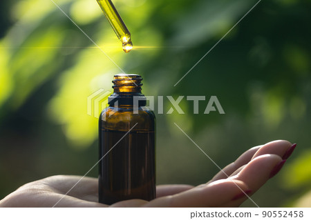 Dripping natural herbal oil into bottle on your hand. Copy space for text. 90552458
