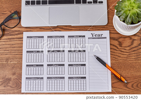 Top view year calendar with pen and plant on wooden desk. Top view year calendar with pen and plant on wooden desk. 90553420