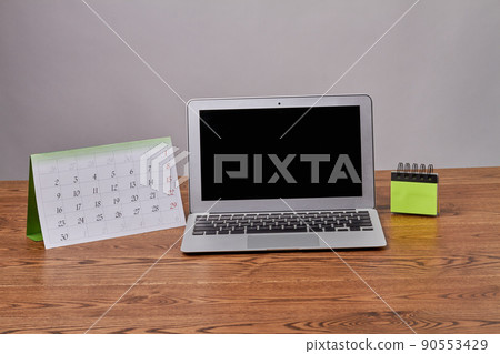 Open laptop with black screen and calendar on wooden desk. Open laptop with black screen and calendar on wooden desk. 90553429