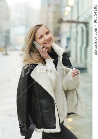 young blond slavic woman with cell phone in black leather jacket closeup street portrait young blond slavic woman with cell phone in black leather jacket closeup street portrait 90554195