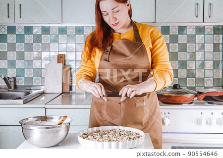 Young woman cooks in home kitchen and photographs food for social media. Blogger writes a culinary blog. Lifestyle, home leisure concept. 90554646