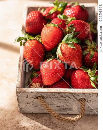 Strawberries in white rustic box on brown textured background with window shadows, close up Strawberries in white rustic box on brown textured background with window shadows, close up 90554868