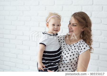 Mother holds and having fun her child with hearing aids and cochlear implants on white brick wall with copy space and place for advertising . Deaf and innovating medicine technologies concept Mother holds and having fun her child with hearing aids and cochlear implants on white brick wall with copy space and place for advertising . Deaf and innovating medicine technologies concept 90555017