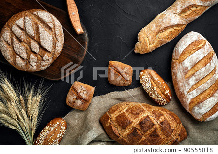 Bakery - gold rustic crusty loaves of bread and buns on black chalkboard background. Bakery - gold rustic crusty loaves of bread and buns on black chalkboard background. 90555018