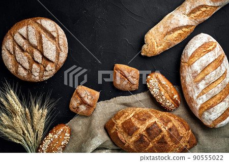 Bakery - gold rustic crusty loaves of bread and buns on black chalkboard background. Bakery - gold rustic crusty loaves of bread and buns on black chalkboard background. 90555022