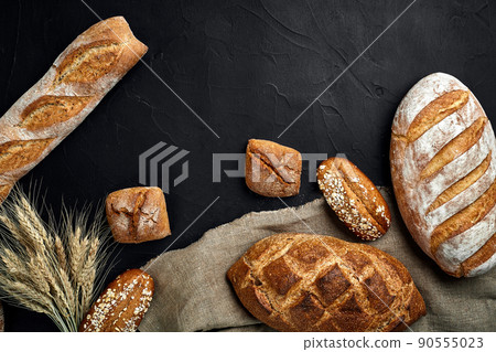 Bakery - gold rustic crusty loaves of bread and buns on black chalkboard background. 90555023