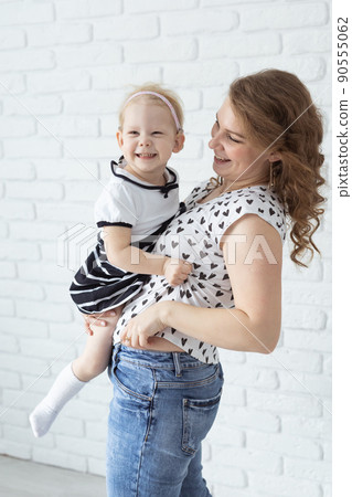 Mother holds her child with hearing aids and cochlear implants on white brick wall with copy space and place for advertising . Deaf and health concept Mother holds her child with hearing aids and cochlear implants on white brick wall with copy space and place for advertising . Deaf and health concept 90555062