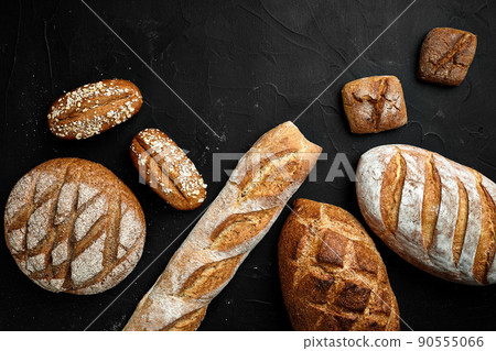 Bakery - gold rustic crusty loaves of bread and buns on black chalkboard background. Bakery - gold rustic crusty loaves of bread and buns on black chalkboard background. 90555066
