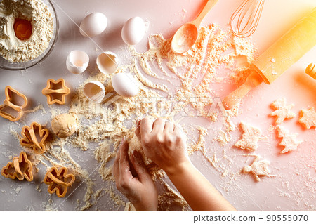 Female hands knead dough with egg and a rolling pin for preparation of cookies. Top view. Sun flare 90555070