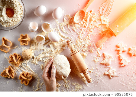 Female hands knead dough with egg and a rolling pin for preparation of cookies. Top view. Sun flare 90555075