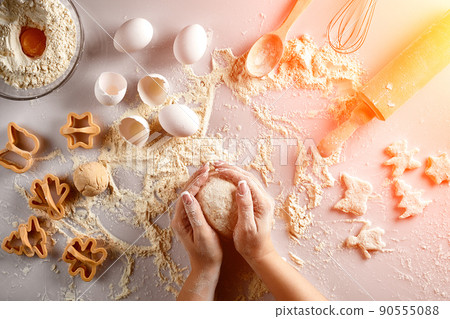 Female hands knead dough with egg and a rolling pin for preparation of cookies. Top view. Sun flare 90555088