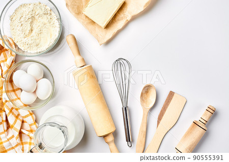 Preparation of the dough. A measurement of the amount of ingredients in the recipe. Ingredients for the dough: flour, eggs, rolling pin, whisk, milk, butter, cream. Top view, space for text 90555391