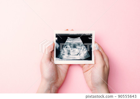 Ultrasound photo pregnancy baby. Woman hands holding ultrasound pregnant picture on pink background. Concept maternity, pregnancy, childbirth. Ultrasound photo pregnancy baby. Woman hands holding ultrasound pregnant picture on pink background. Concept maternity, pregnancy, childbirth. 90555643