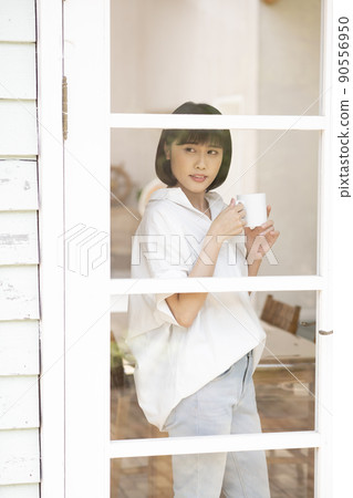 透過玻璃格子門向外看的年輕女子 90556950