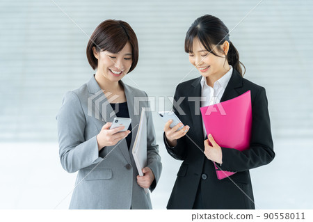 Female businessmen, female employees using smartphones 90558011