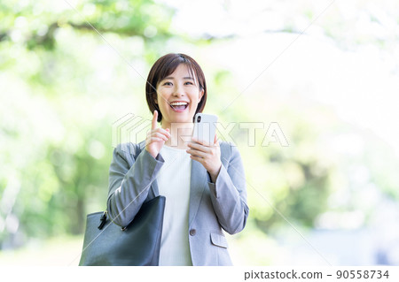 A woman in a suit who uses a smartphone, a business woman A woman in a suit who uses a smartphone, a business woman 90558734