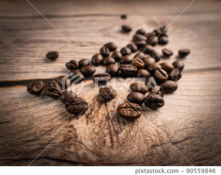 Close up shot of coffee beans was poured on the wooden floor focus at some point Gives a warm light to a warm mood insert a little darkness shooting in the studio Close up shot of coffee beans was poured on the wooden floor focus at some point Gives a warm light to a warm mood insert a little darkness shooting in the studio 90559846