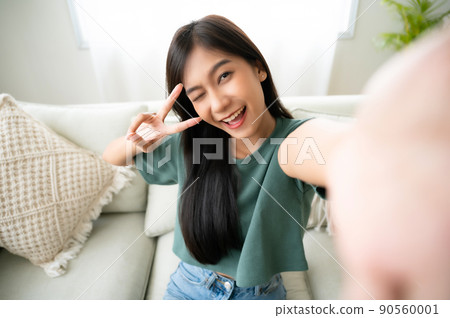 Pretty young asian female with big smile sitting at living room 90560001