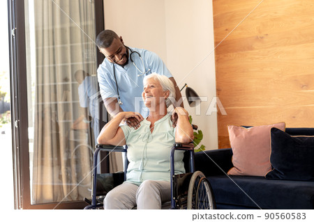 African american male health worker supporting caucasian senior woman sitting on the wheelchair African american male health worker supporting caucasian senior woman sitting on the wheelchair 90560583