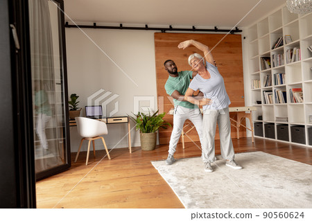 African american male physiotherapist helping caucasian senior woman to perform stretching exercise 90560624