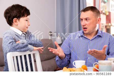 Offended son and unhappy father having quarrel in living room Offended son and unhappy father having quarrel in living room 90561169