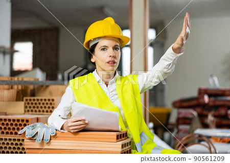 Strict female supervisor making stop gesture while inspecting construction site Strict female supervisor making stop gesture while inspecting construction site 90561209