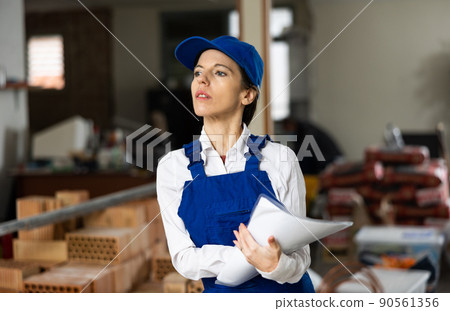 Positive female civil engineer taking notes while checking indoor construction site, satisfied with progress of work 90561356