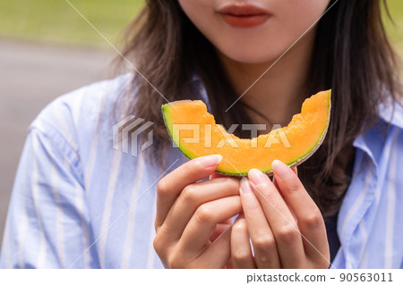 A woman trying to eat melon melon A woman trying to eat melon melon 90563011