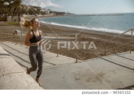 Cheerful and beautiful sporty woman jogging outdoors Cheerful and beautiful sporty woman jogging outdoors 90565102