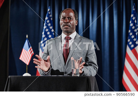 African American mature politician standing at platform and presenting is report at formal conference 90566590