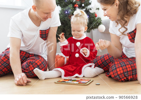 Toddler child with cochlear implant plays with parents under christmas tree - deafness and diversity and innovating medical technologies for hearing aid 90566928