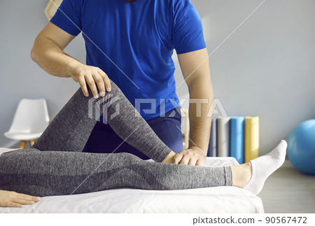 Chiropractor or physiotherapist treating leg pain and examining knee flexion of young woman 90567472