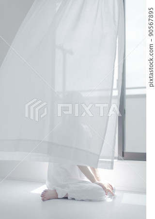 A woman sitting in a white room and by the window A woman sitting in a white room and by the window 90567895