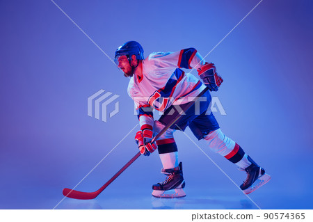 In action. Professional hockey player in sports uniform and protective equipment skating isolated on purple background. Concept of sport, active lifestyle, motion, movement, ad. 90574365