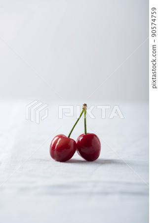 Two cherries on the white linen tablecloth 90574759