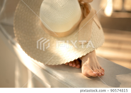women's feet peek out from under straw hat, close up summer outfit women's feet peek out from under straw hat, close up summer outfit 90574815