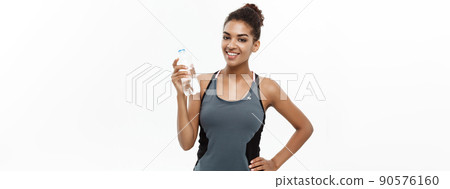 Healthy and Fitness concept - beautiful African American girl in sport clothes holding plastic water bottle after workout. Isolated on white studio background 90576160