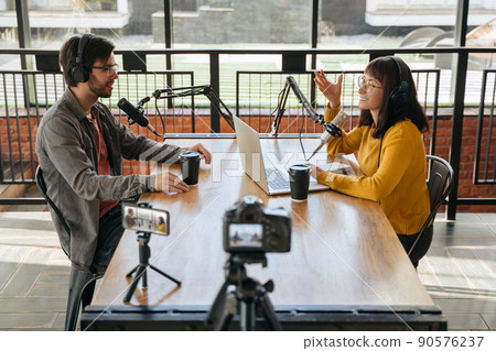 Two podcasters recording video podcast together in studio Two podcasters recording video podcast together in studio 90576237