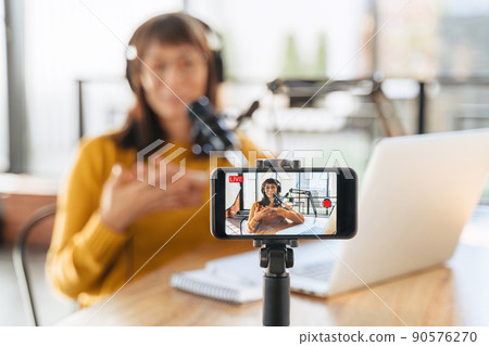 Woman vlogger speaking on smartphone camera while shooting live video podcast Woman vlogger speaking on smartphone camera while shooting live video podcast 90576270