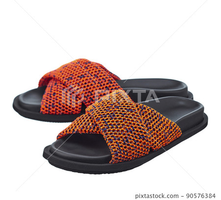 Beautiful pair of high-quality sandals with a bright orange brained top and a black leather sole, isolated on a white background. Comfortable shoes for beach holidays and summer walks. 90576384