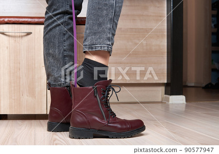 Woman putting on red shoes using shoehorn Woman putting on red shoes using shoehorn 90577947