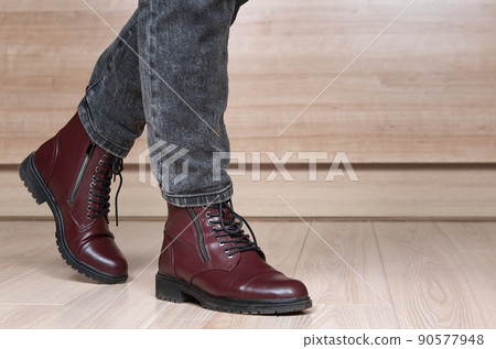 Closeup of stepping woman legs in red leather boots and black jeans 90577948