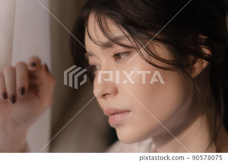 Portrait of a woman standing by the window 90578075