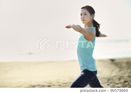 在海灘上做瑜伽的年輕女子 90578669