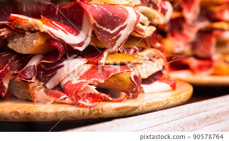 traditional Spanish bocadillos with Iberico jamon laid out in a slide on a shop window 90578764