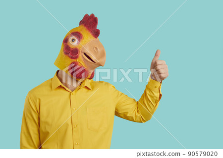 Funny man with chicken head raises his thumb up demonstrates you OK gesture, consent or his support. Funny man with chicken head raises his thumb up demonstrates you OK gesture, consent or his support. 90579020